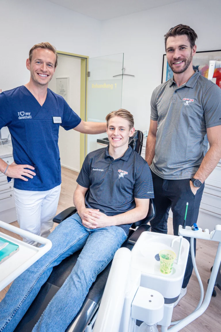 Zwei Spieler der Kölner Haie mit Dr. Alexander Langenbach