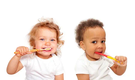 Zwei Babys, welche mit einer Zahnbürste im Mund spielen