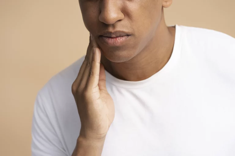 Ein Mann fasst sich an seinen Kiefer.