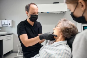 Ein Zahnarzt untersucht die Zähne einer älteren Patientin.